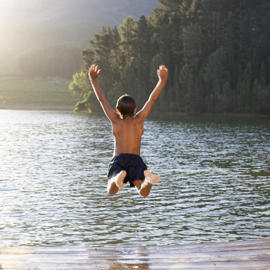 Barn hoppar i sjö från brygga