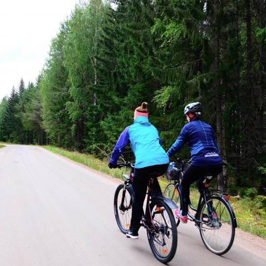 Två kvinnor som cyklar på grusväg i skogslandskap