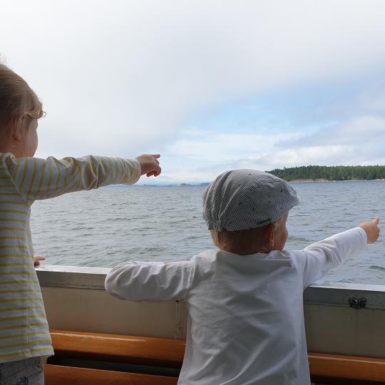 Två barn som pekar mot strand från båt