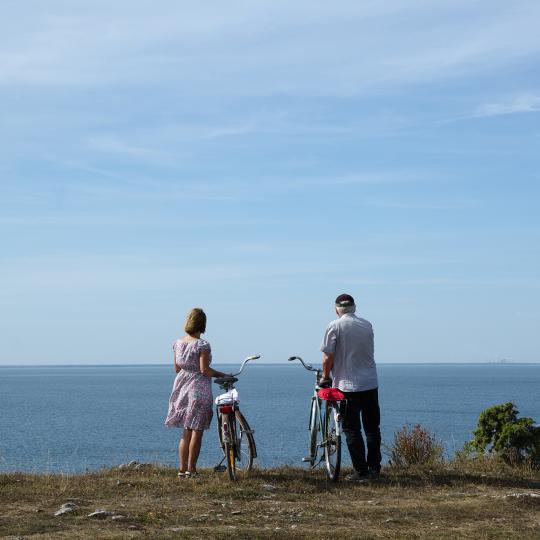 Ett par som står med cyklar och tittar på utsikten över havet