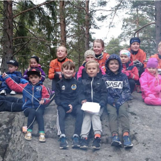 Barn som sitter på en stenhäll i skogen