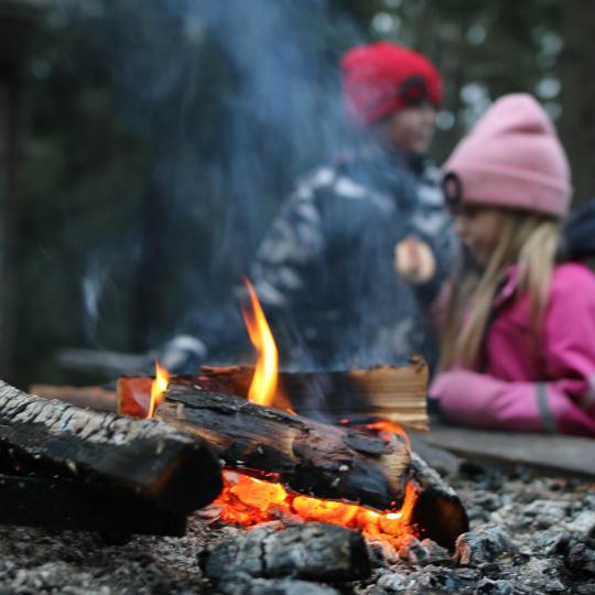 Två barn som grillar korv vid öppen eld