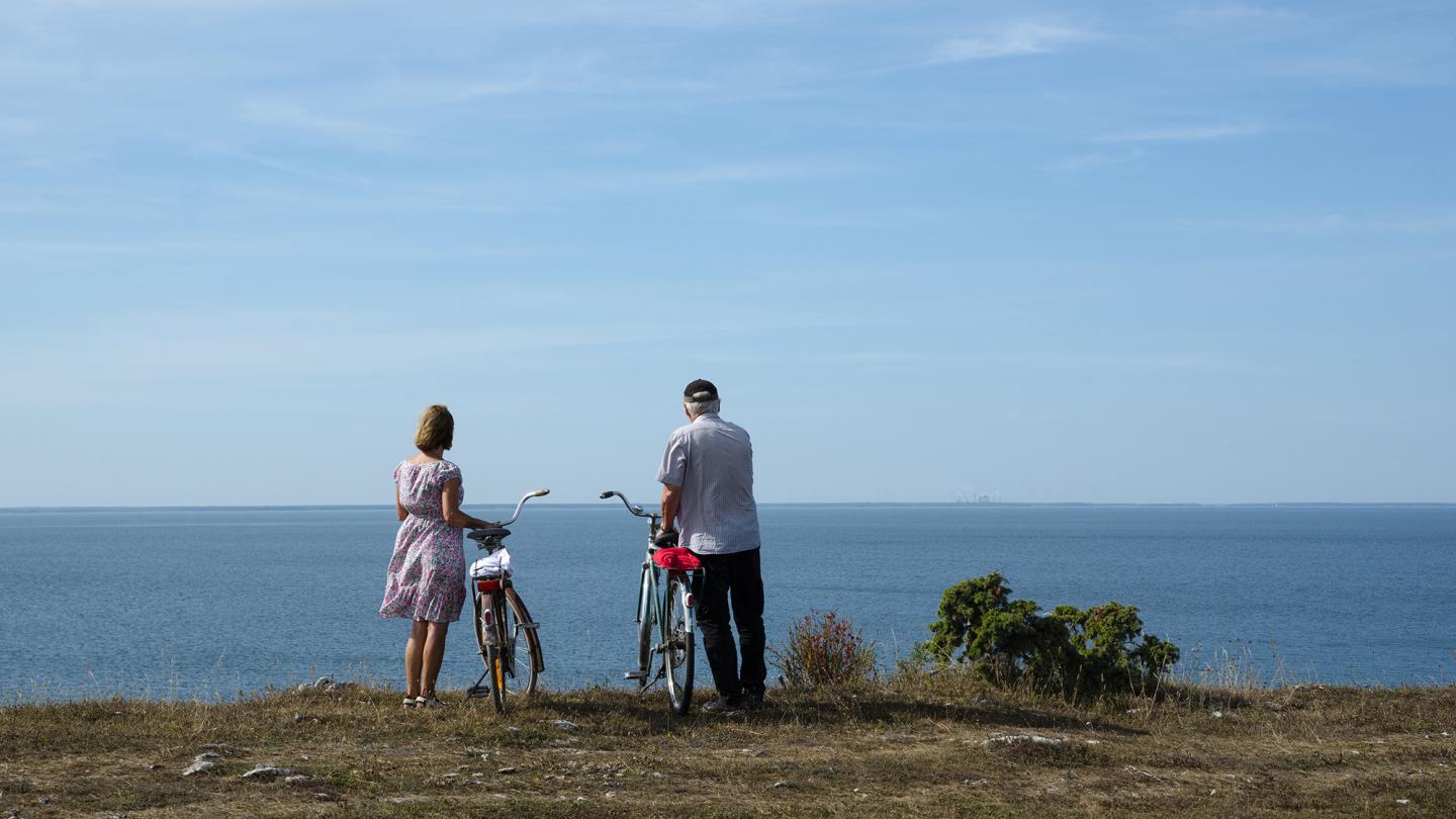 Ett par som står med cyklar och tittar på utsikten över havet